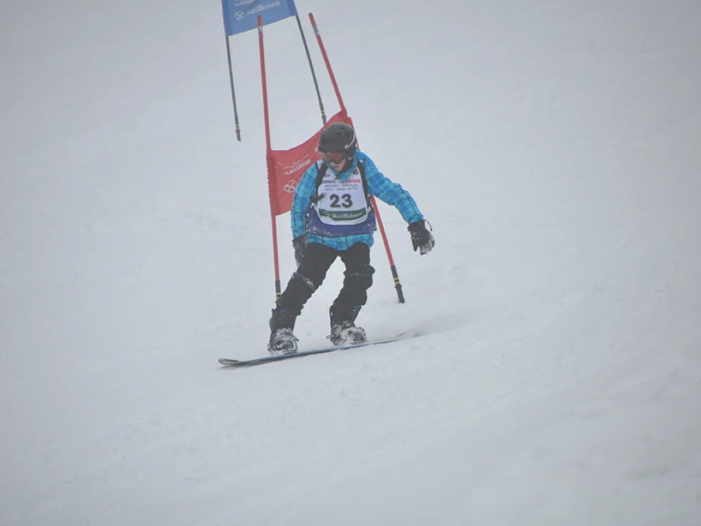Snowboarder mit Startnummer 23 umfährt ein rotes Tor.
